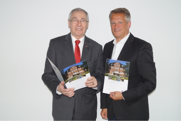 Kreispräsident Burkhard E. Tiemann (links) und Landrat Oliver Stolz mit dem Infoflyer des neuen Kreisbuches